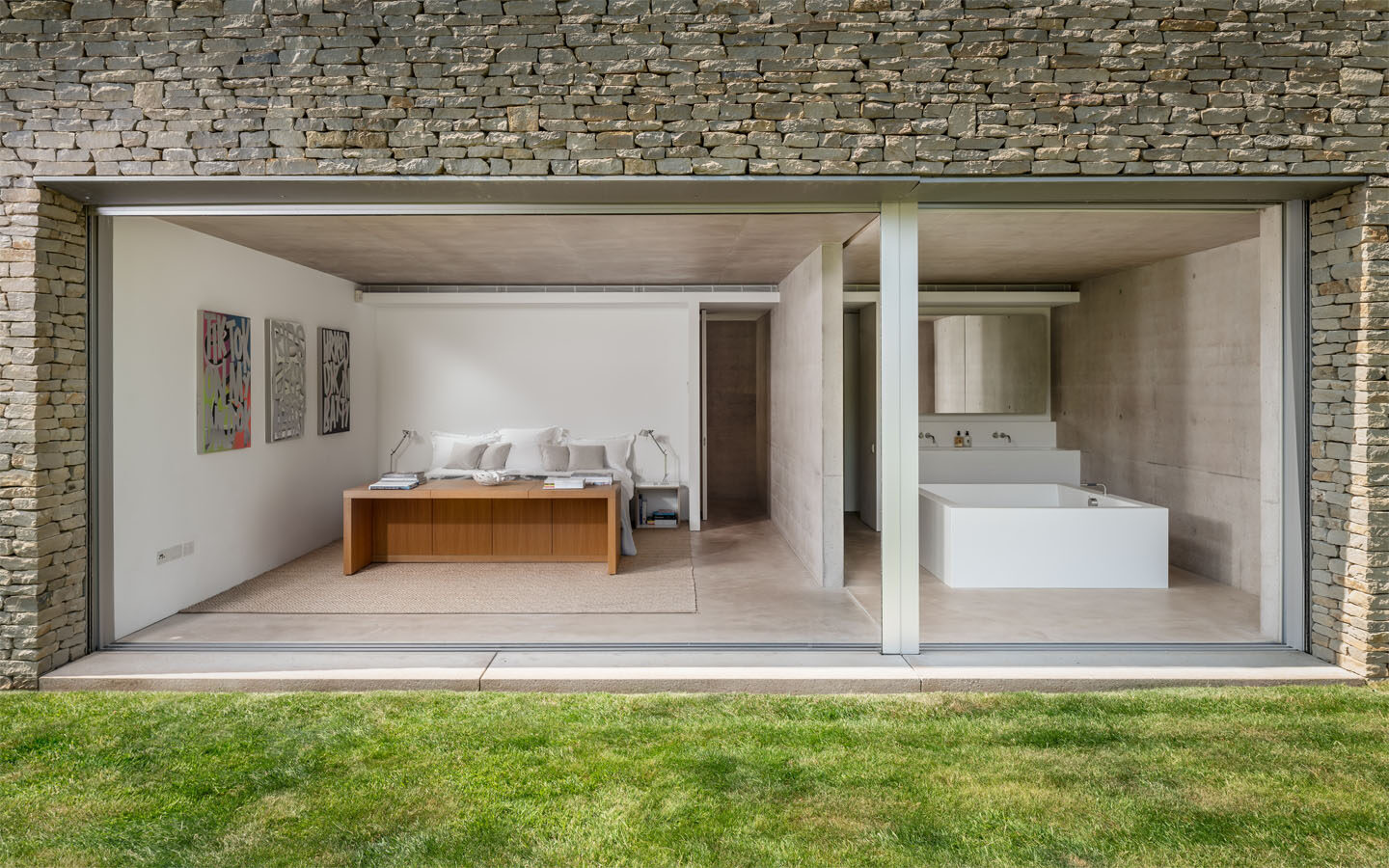 Modern open-plan bedroom and bathroom with stone façade.