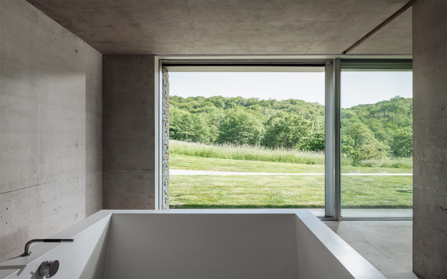 Modern bathroom with large window, nature view.