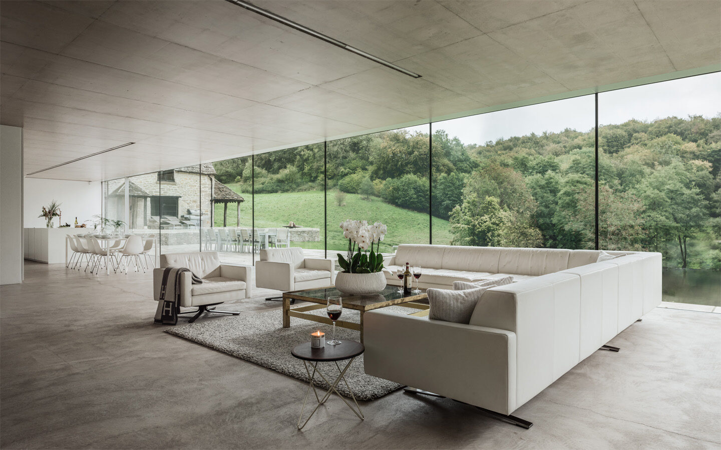 Modern living room with glass walls and countryside view.