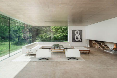 Modern living room with glass walls and fireplace.