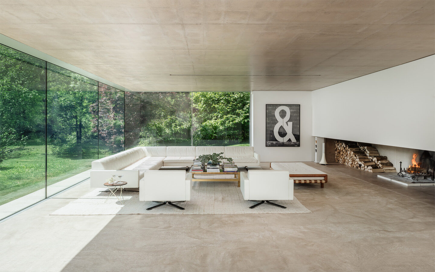 Modern living room with glass walls and fireplace.