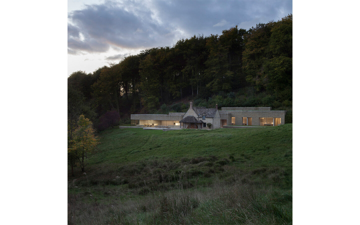 Modern house at forest edge during sunset.