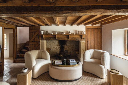 Rustic living room with wooden beams and cosy chairs.