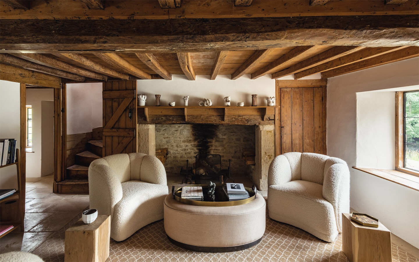 Rustic living room with wooden beams and cosy chairs.