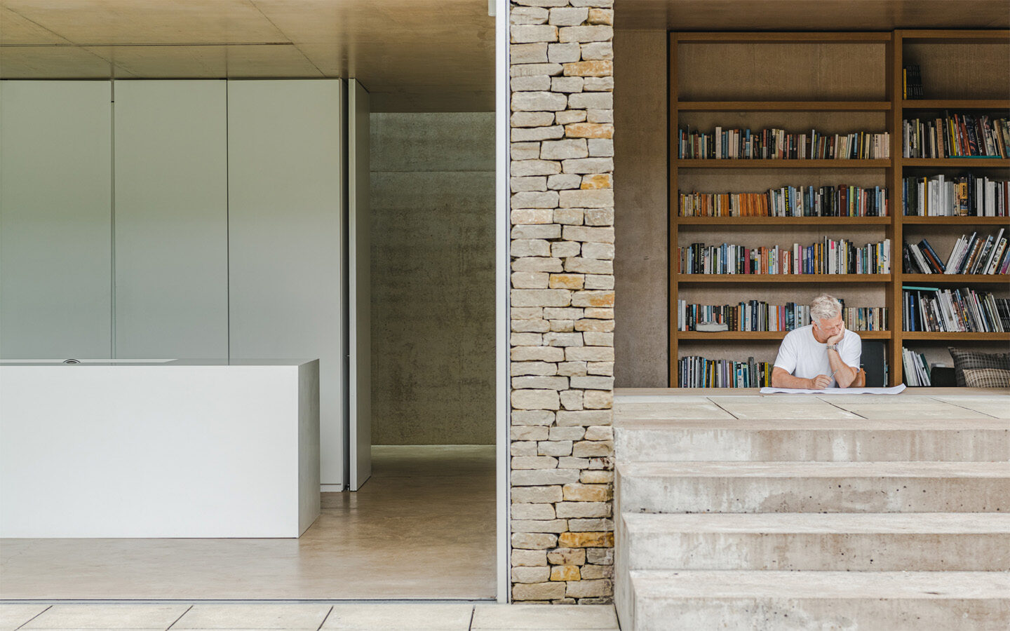 Modern library with stone wall and thoughtful reader.