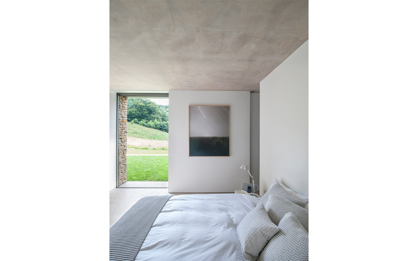 Minimalist bedroom with countryside view through open window.