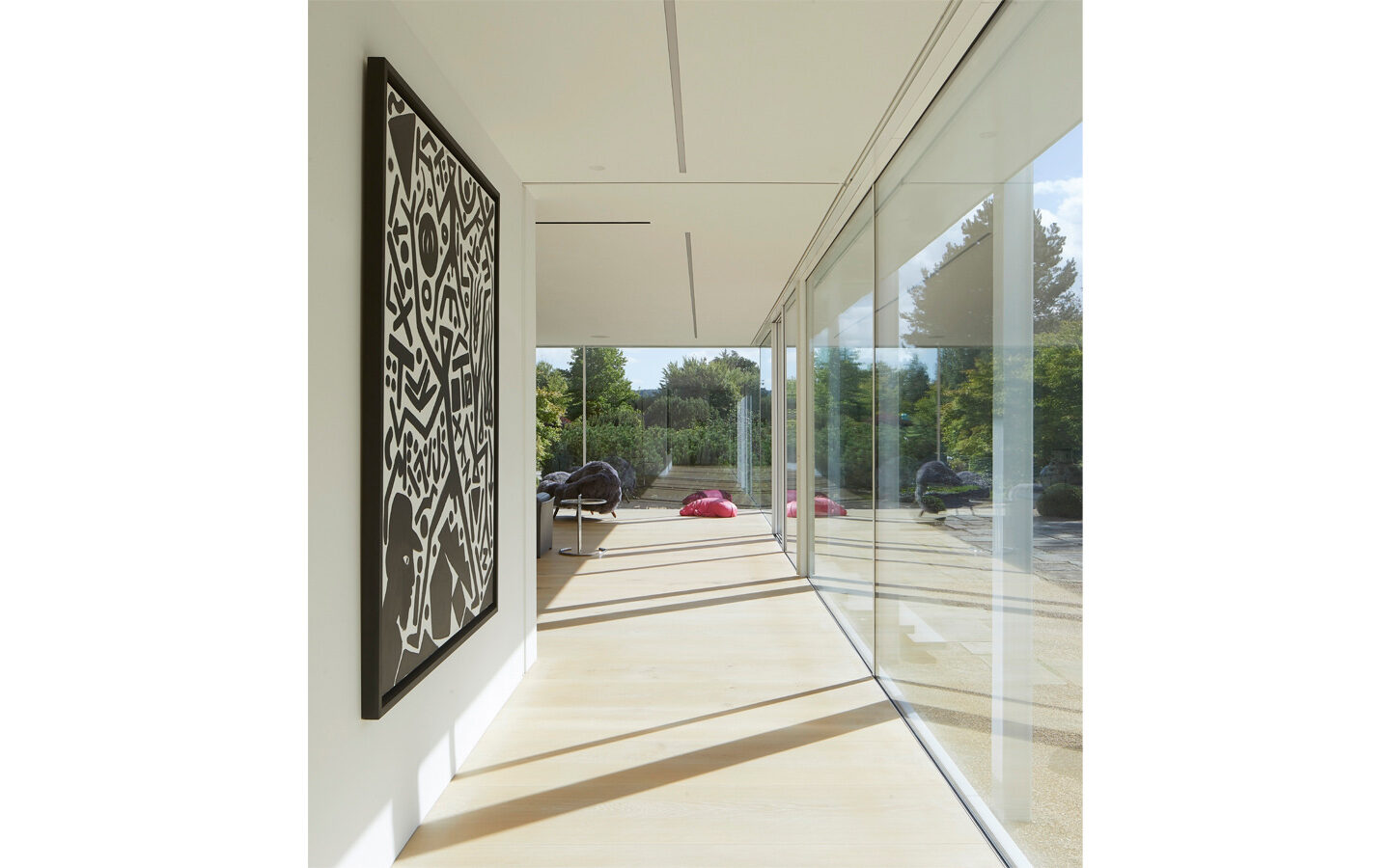 Modern hallway with abstract painting and glass wall.
