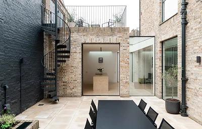 Modern courtyard with brick walls and spiral staircase.