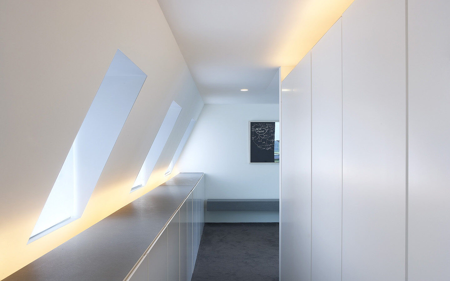 Minimalist hallway with slanted windows and white walls.