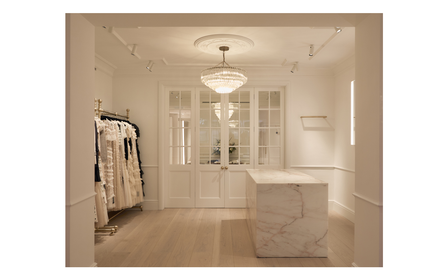 Elegant boutique interior with chandelier, clothes, marble counter.