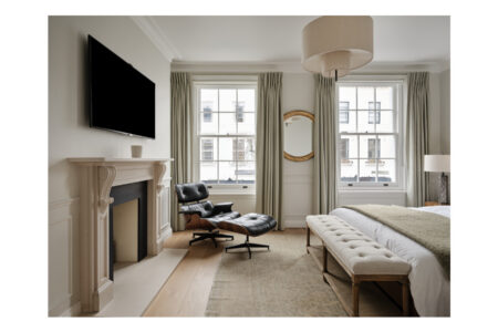 Elegant bedroom with fireplace, armchair, and large windows.