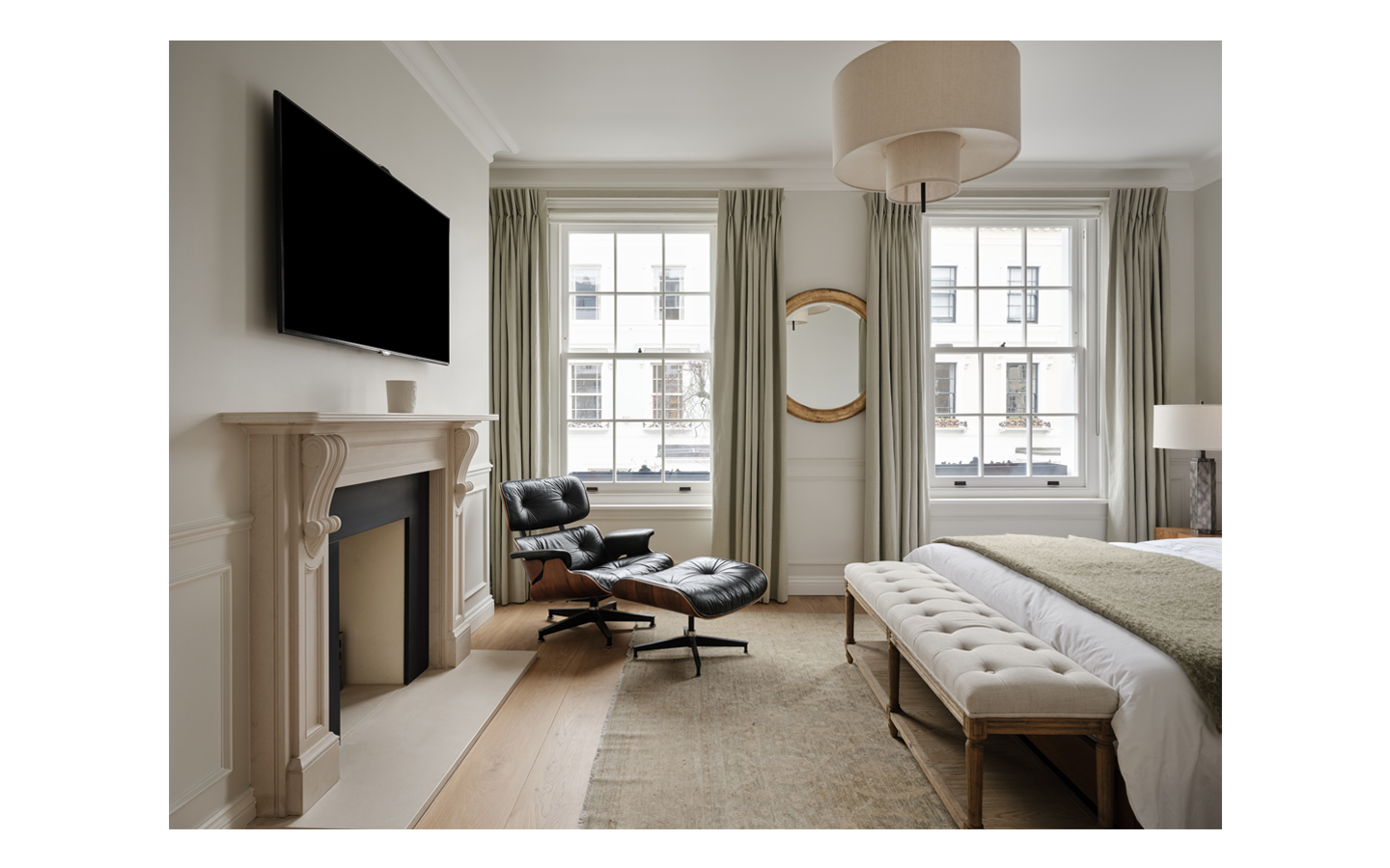 Elegant bedroom with fireplace, armchair, and large windows.