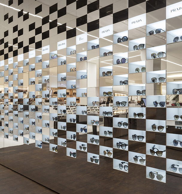Wall display of designer sunglasses in store.